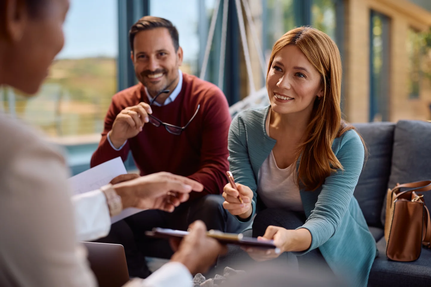Glimlachend stel tekent een contract met een makelaar, met focus op de vrouw.