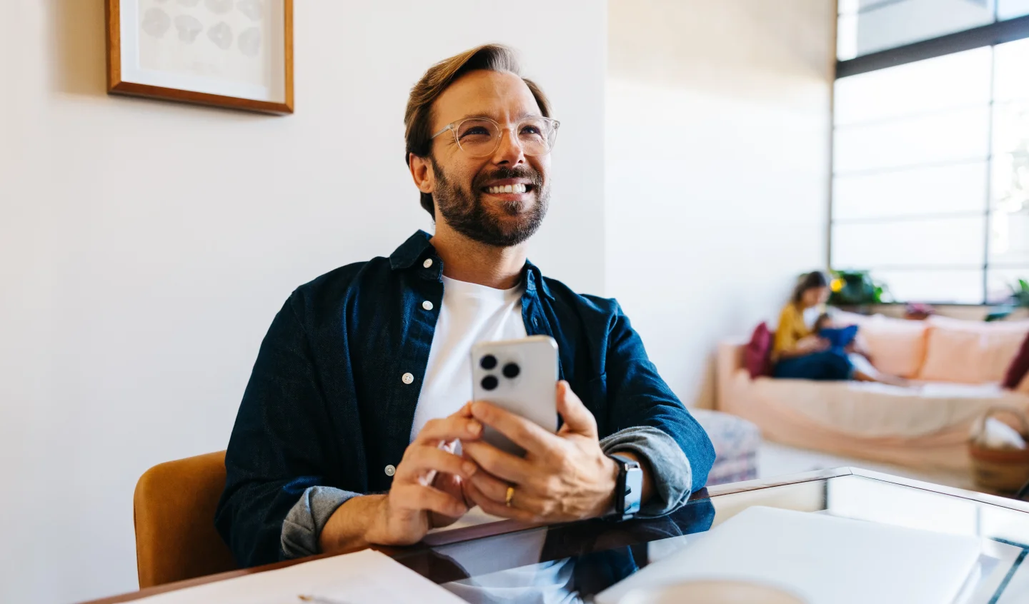 Man lacht met telefoon in zijn hand in een modern café