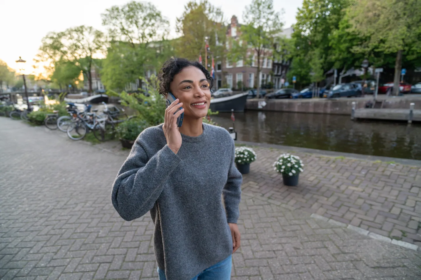 Expat woman on the phone walking along an Amsterdam canal.