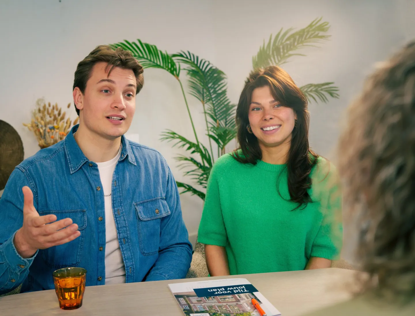 Stel in gesprek met een adviseur aan tafel over verzekeringen en hun woonsituatie.